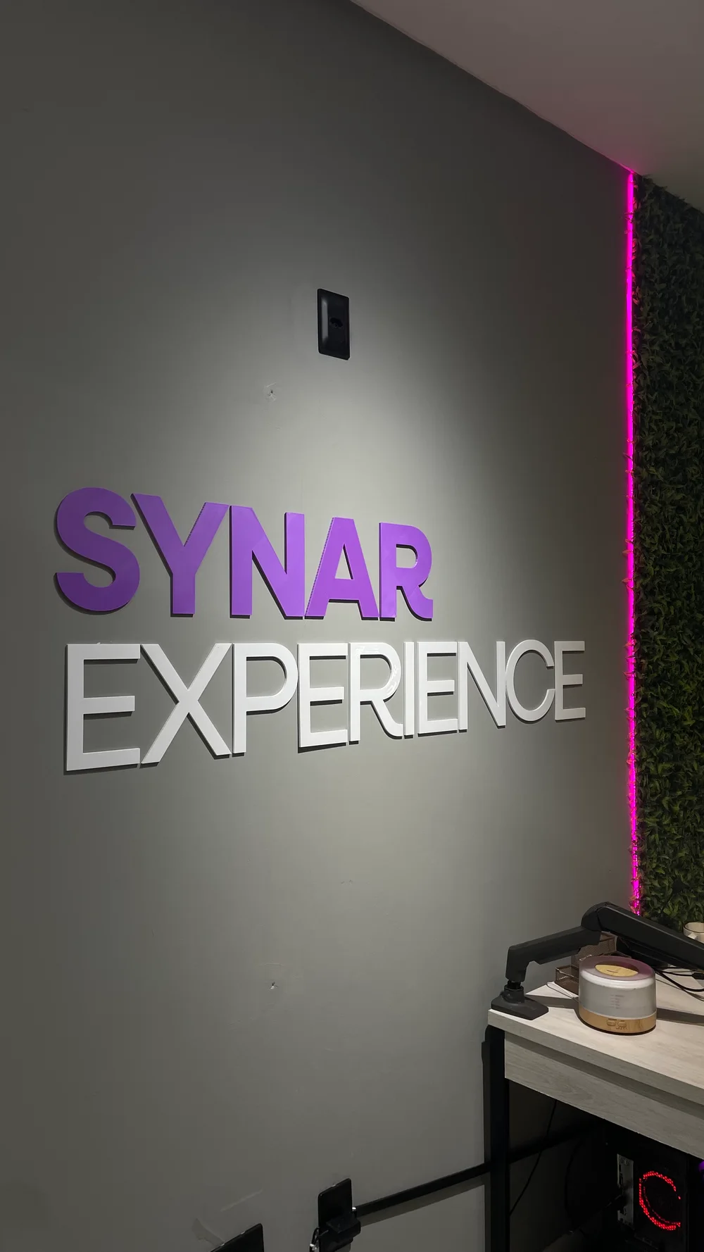 O nome Synar Experience na parede do escritório
